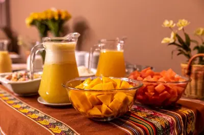 a table with orange juice and fruit on it at Hotel Ferré Boulevard in Machu Picchu