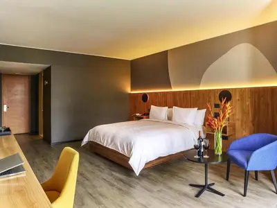a bedroom with a bed and a table and a chair at Pullman Lima San Isidro in Lima