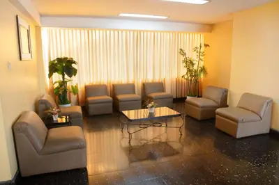 a waiting room with couches and a table and chairs at Hotel Olaya in Lima