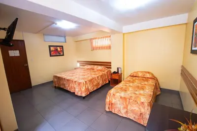 a hotel room with two beds and a table at Hotel Olaya in Lima