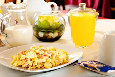 a plate of food on a table with milk and orange juice at Hotel Olaya in Lima