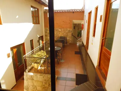 a corridor of a building with a staircase and chairs at Kutty Wasi in Cusco