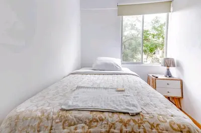 a bed in a white room with a window at Green House in Lima