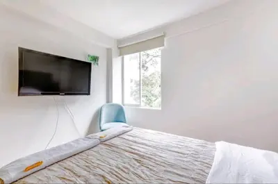 a bedroom with a bed with a flat screen tv on the wall at Green House in Lima