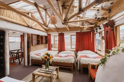 a room with two beds and a vase of flowers on a table at Hostal Madre Tierra in Cusco