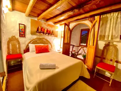 a bedroom with a large bed with two red chairs at Hostal Madre Tierra in Cusco