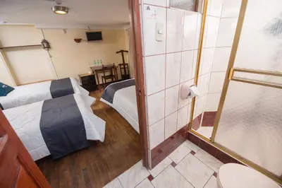 a small room with a bed and a shower at Ayenda Casa Escondida San Cristóbal Premium in Cusco