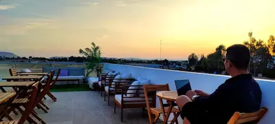 a man sitting on a balcony with a laptop at Paracas Guest House in Paracas