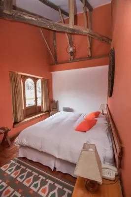 a bedroom with a large bed with orange walls at SAUCE Hotel Boutique in Ollantaytambo