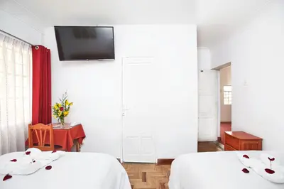 a bedroom with two beds and a tv on the wall at Hostal Danna Inn in Cusco