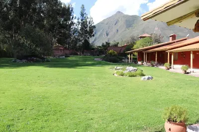 a yard with a green lawn with mountains in the background at Hotel Villa Urubamba in Urubamba