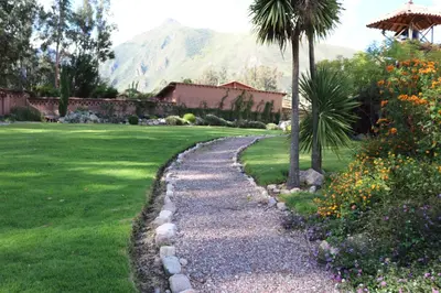a gravel path in a garden with a palm tree at Hotel Villa Urubamba in Urubamba