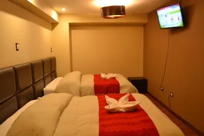 a hotel room with two beds and a tv at Hotel Royal Qosqo in Cusco