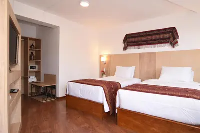 a hotel room with two beds and a tv at Hotel Prisma Cusco in Cusco
