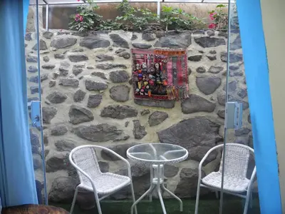 a stone wall with two chairs and a table at Ccapac Inka Ollanta Casa Museo in Ollantaytambo