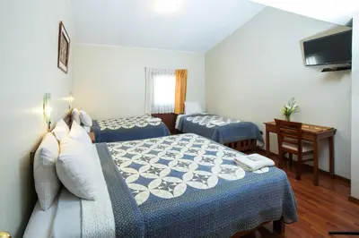 a hotel room with two beds and a desk at Antawasi Hotel in Cusco
