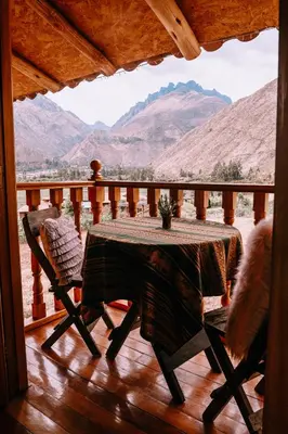 a table and chairs on a porch with a view of mountains at Inkasaire Boutique Lodge in Urubamba