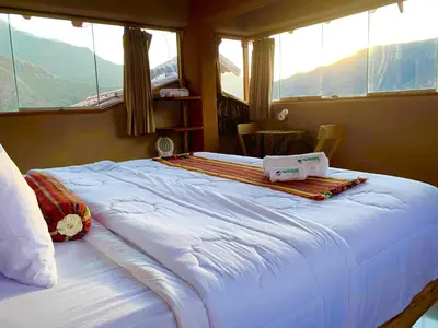 a large bed in a room with windows at Inkasaire Boutique Lodge in Urubamba