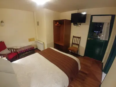 a bedroom with a bed and a desk and a tv at Hostal Corihuasi in Cusco