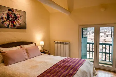a bedroom with a bed and a large window at Hostal Corihuasi in Cusco