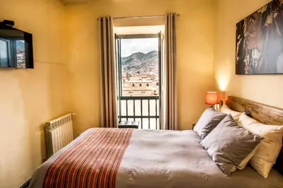 a bedroom with a bed and a window with a view at Hostal Corihuasi in Cusco