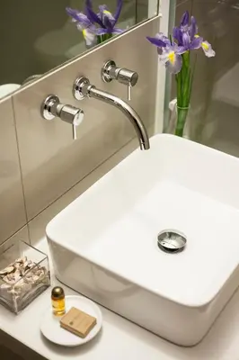 a white bathroom sink with a vase of purple flowers at El Angolo in Lima