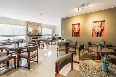 a dining room with tables and chairs and paintings on the wall at Tambo Dos de Mayo in Lima