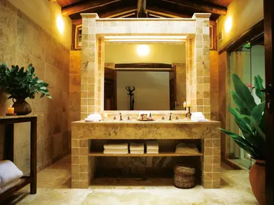 a bathroom with a stone sink and a mirror at Inkaterra Machu Picchu Pueblo Hotel in Machu Picchu