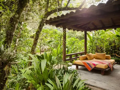 a bench sitting under a pergola in the forest at Inkaterra Machu Picchu Pueblo Hotel in Machu Picchu