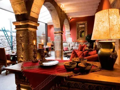 a living room with a table with a lamp on it at Inkaterra La Casona Relais & Chateaux in Cusco