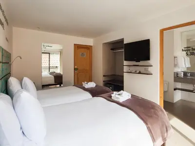 a hotel room with two beds and a television at El MaPi by Inkaterra in Machu Picchu