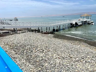 a pier on a rocky beach next to the water at Duplex 1 Fila Vista Bahía Paracas - Sotavento 501 T3 in Paracas