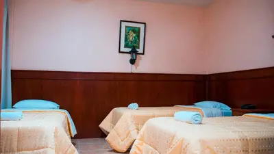 a room with three beds with a picture on the wall at Hotel Princess in Ica