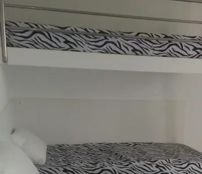 a white bedroom with a bed with a black and white blanket at Condominios Nauticos Nuevo Paracas in Paracas