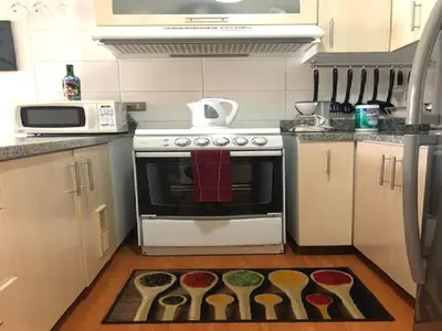a kitchen with a stove with spoons on the floor at A Perfect Vacation Getaway Apartment in Lima