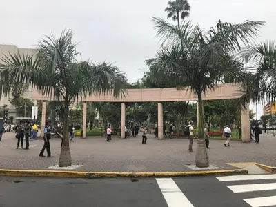 a group of people walking around a plaza with palm trees at A Perfect Vacation Getaway Apartment in Lima