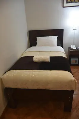 a bedroom with a bed with a blanket on it at Machupicchu Guest House in Machu Picchu