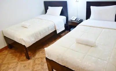 a hotel room with two beds and a stool at Machupicchu Guest House in Machu Picchu