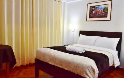 a bedroom with a large bed with white sheets at Machupicchu Guest House in Machu Picchu