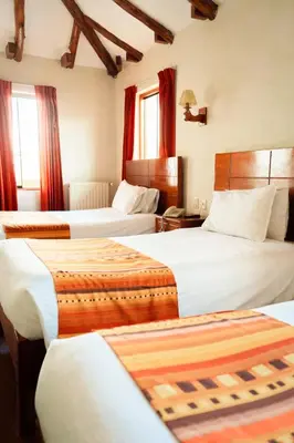 a hotel room with three beds with red curtains at Siete Ventanas in Cusco