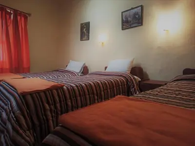 a group of three beds in a room at Hostal Tu Hogar in Cusco