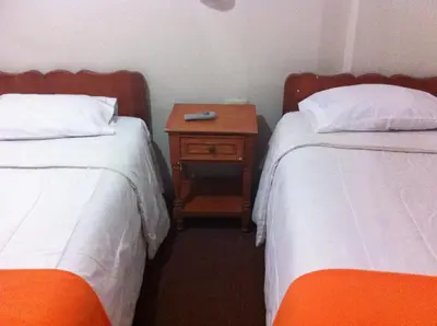 a hotel room with two beds and a nightstand between them at Hostal Tu Hogar in Cusco