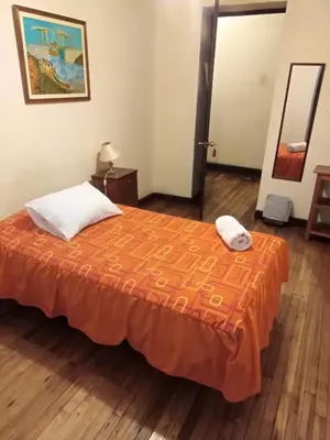 a bedroom with a bed with an orange bedspread at El Tuco Hotel in Cusco