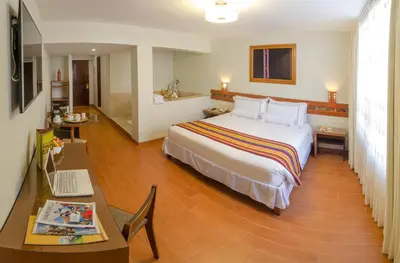 a hotel room with a bed and a desk and aaptop at Taypikala Hotel Cusco in Cusco