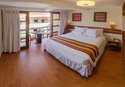 a bedroom with a large bed and a balcony at Taypikala Hotel Cusco in Cusco