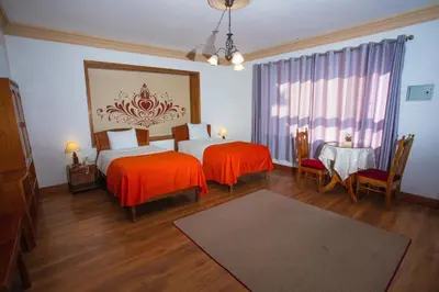 a bedroom with two beds with orange sheets and a table at Centenario Inn in Cusco