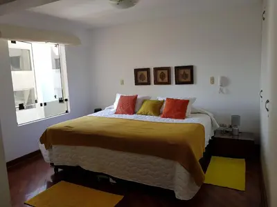 a bedroom with a large bed with orange and yellow pillows at Malecón in Lima