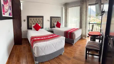 a bedroom with two beds with red pillows at Hotel Quilla in Urubamba
