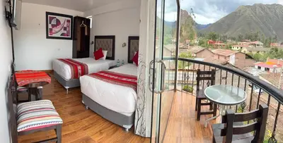 a room with two beds and a balcony with a view at Hotel Quilla in Urubamba