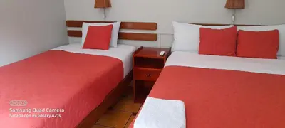 two beds in a hotel room with red and white sheets at Hostal La Payacha MachuPicchu in Machu Picchu
